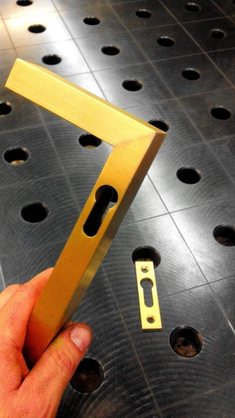 A machined brass bracket on the fixture table