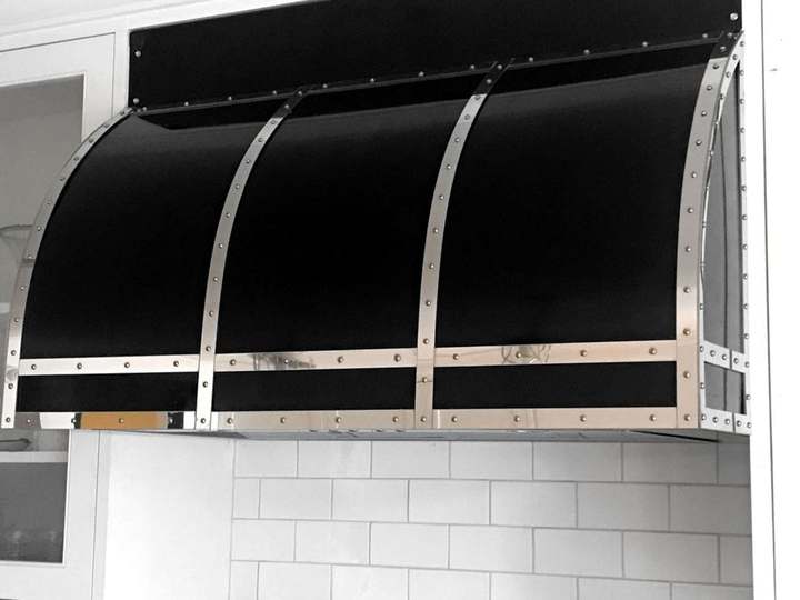 Curved black steel range hood with bright straps